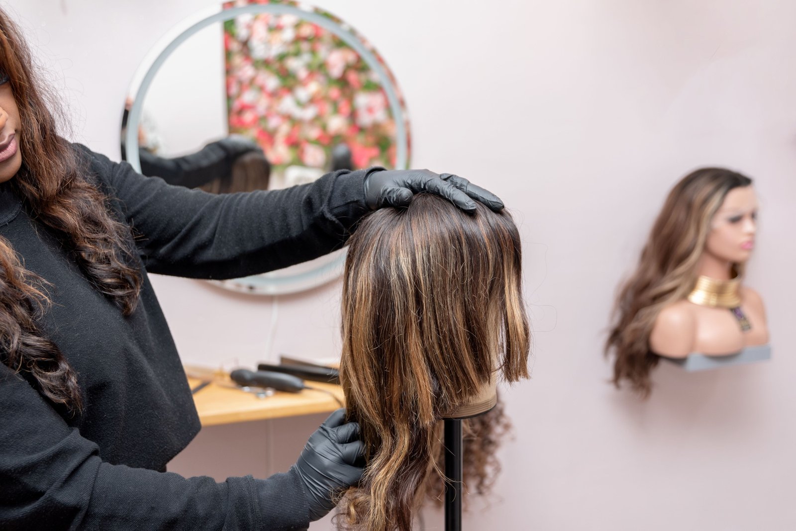 african american Hairdresser fitting mannequin head with oncologic wig